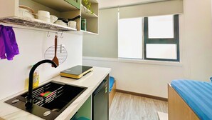 A compact kitchen with a sink, a stove, and a window. - Loftic Apartments - Pink Church (Ho Chi Minh City)