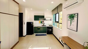 A modern kitchen with a built-in washing machine, a dining area with a bench, and a window with a view. - Loftic Apartments - Pink Church (Ho Chi Minh City)