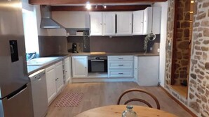 Una cocina con armarios blancos, horno empotrado y refrigerador.