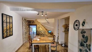 Un comedor con una mesa y sillas de madera, una escalera, y una pared con un reloj y adornos decorativos.