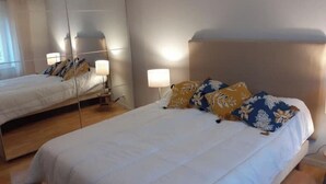 Una habitación de hotel con una cama grande, lámparas de noche y un espejo.