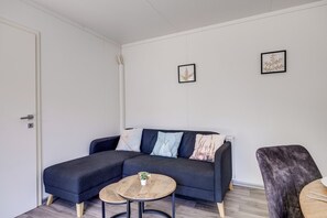 A modern living room with a dark sofa, two small round tables, and a dark armchair. - Cube 11 | Cabin in the Fruits | Zennewijnen, Betuwe (Zennewijnen)