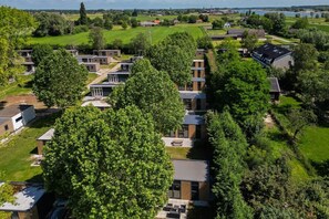 A residential area with modern houses, green lawns, and a lake in the background.
