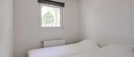 Un dormitorio con una cama individual, una ventana con persiana y un radiador.