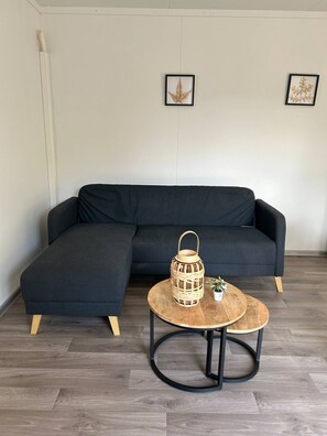 A modern living room with a sectional sofa, a round coffee table with a lantern, and two framed wall art pieces.