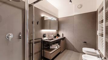 Un baño moderno con ducha de vidrio, tocador con espejo y retrete.
