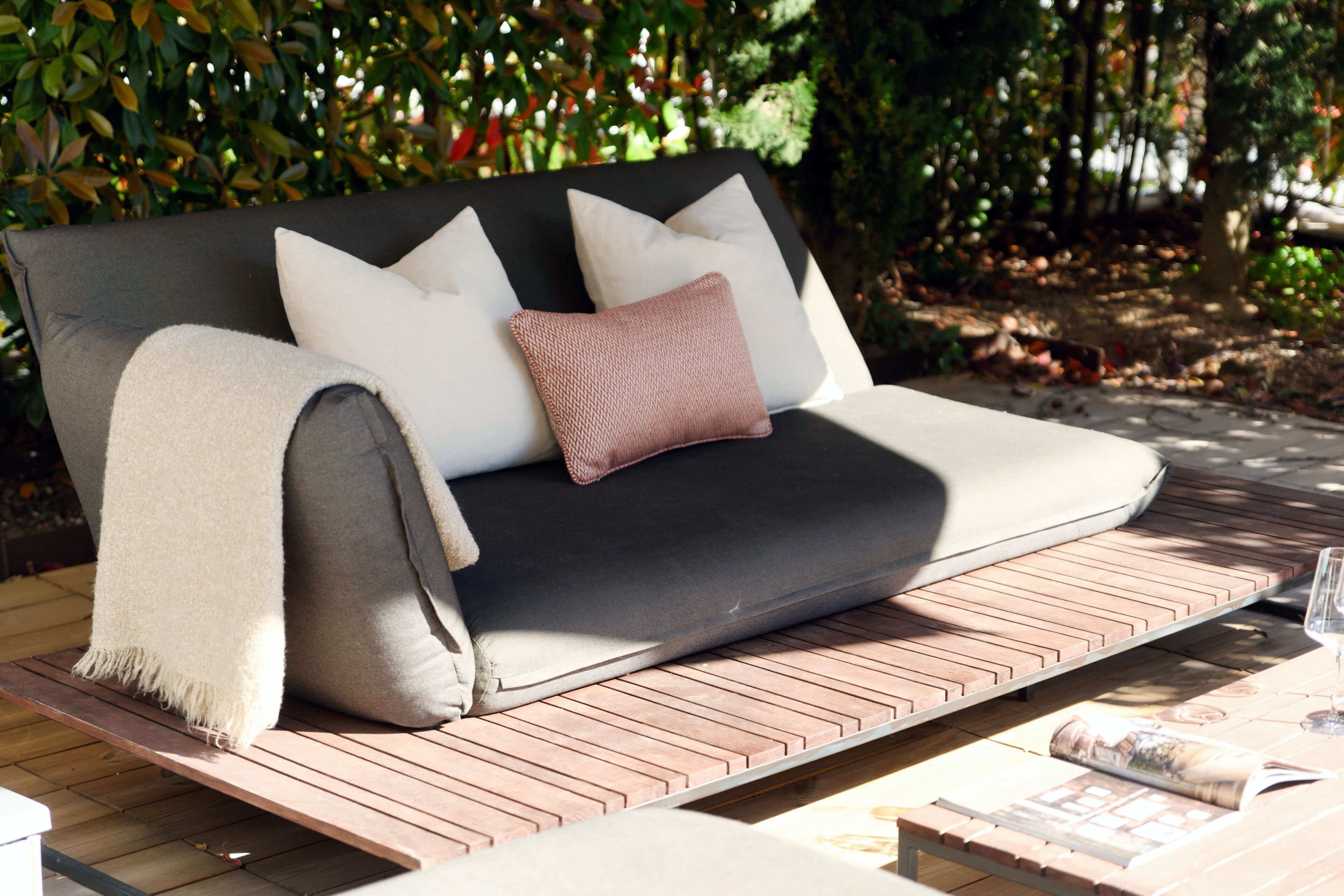 Un divano con cuscini e una coperta, un tavolino di legno e una rivista.