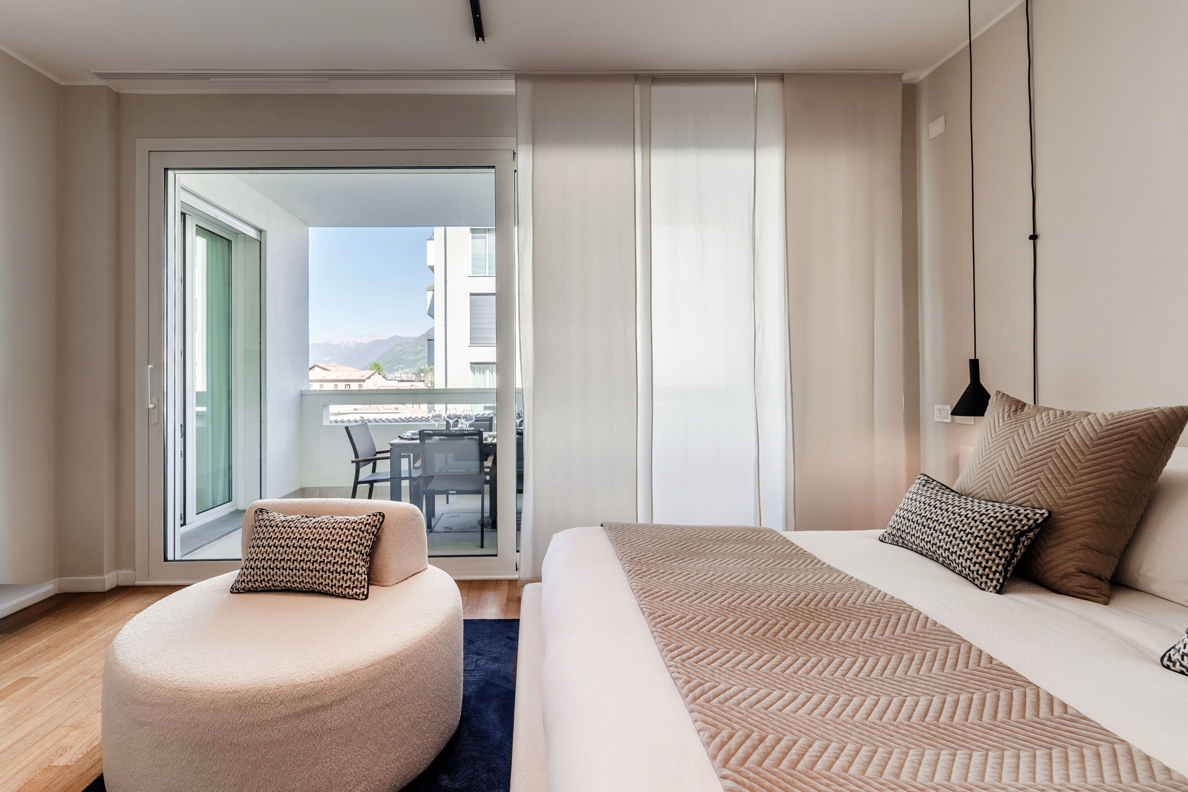 A modern hotel room with a bed, a seating area, and a view of the city.