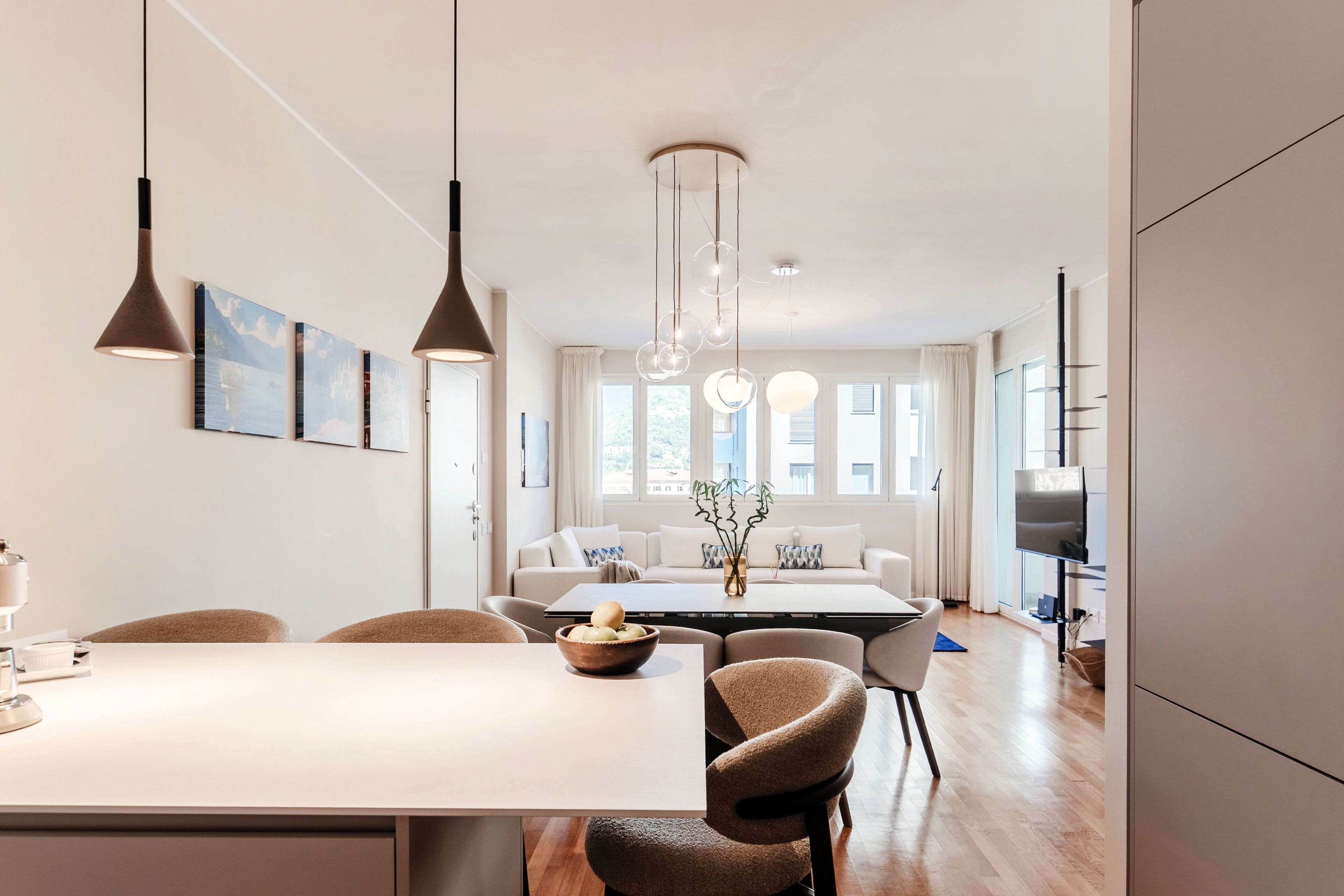 A modern living room with a dining area, a sofa set, a TV, and a large window.