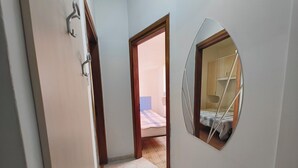 A narrow hallway with a door leading to a bedroom with a bed and a small table. - Familiar Base for a Comfortable Stay in Rosolina (Rosolina)