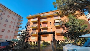 A multi-story residential building with balconies, a gated entrance, and parked cars. - Familiar Base for a Comfortable Stay in Rosolina (Rosolina)