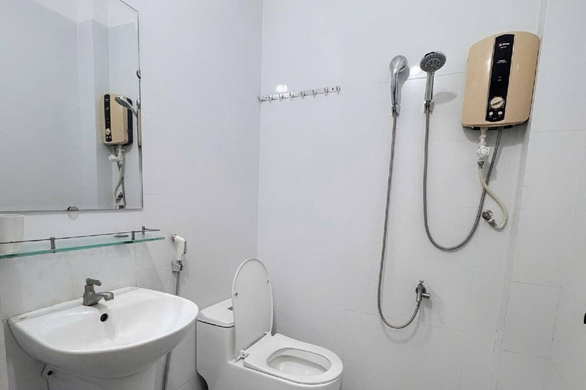 Un baño con inodoro, lavamanos y cabezal de ducha manual.
