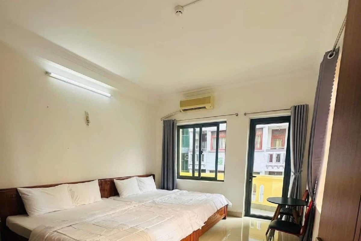 Habitación de hotel con una cama grande, una mesita, una silla, una ventana con cortinas y vistas al exterior.
