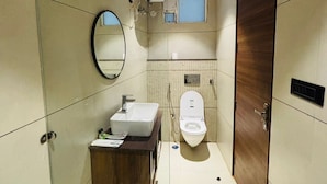 A modern bathroom with a glass shower enclosure, a wooden vanity, a toilet, and a mirror. - Hotel Hrishikesh High Tapovan 2.0 (Rishikesh)
