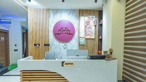 A reception desk with a sign, a computer, and a small statue. - Hotel Hrishikesh High Tapovan 2.0 (Rishikesh)