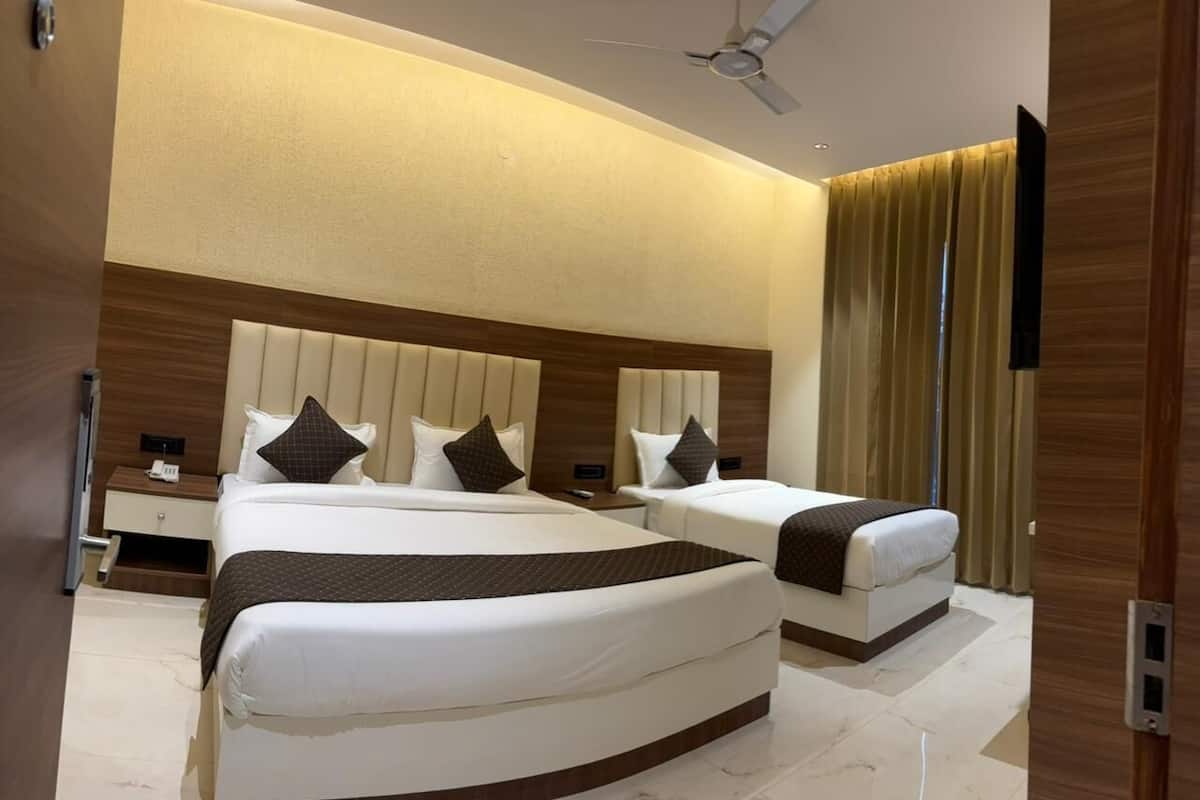 A hotel room with two beds, a ceiling fan, a TV, and a wooden headboard.