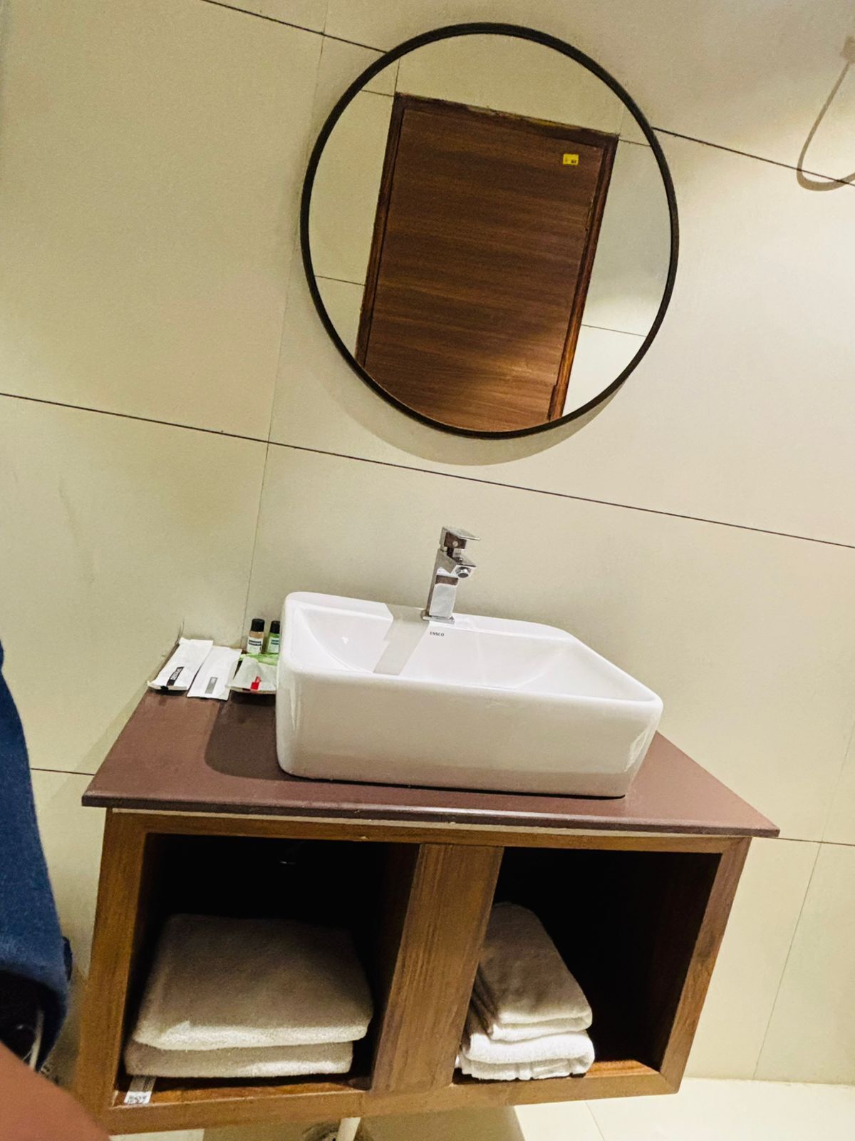 A bathroom with a white sink, a mirror, and a wooden cabinet with towels.