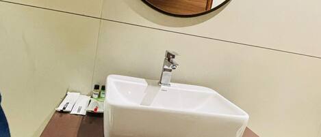 A bathroom with a white sink, a mirror, and a wooden cabinet with towels.