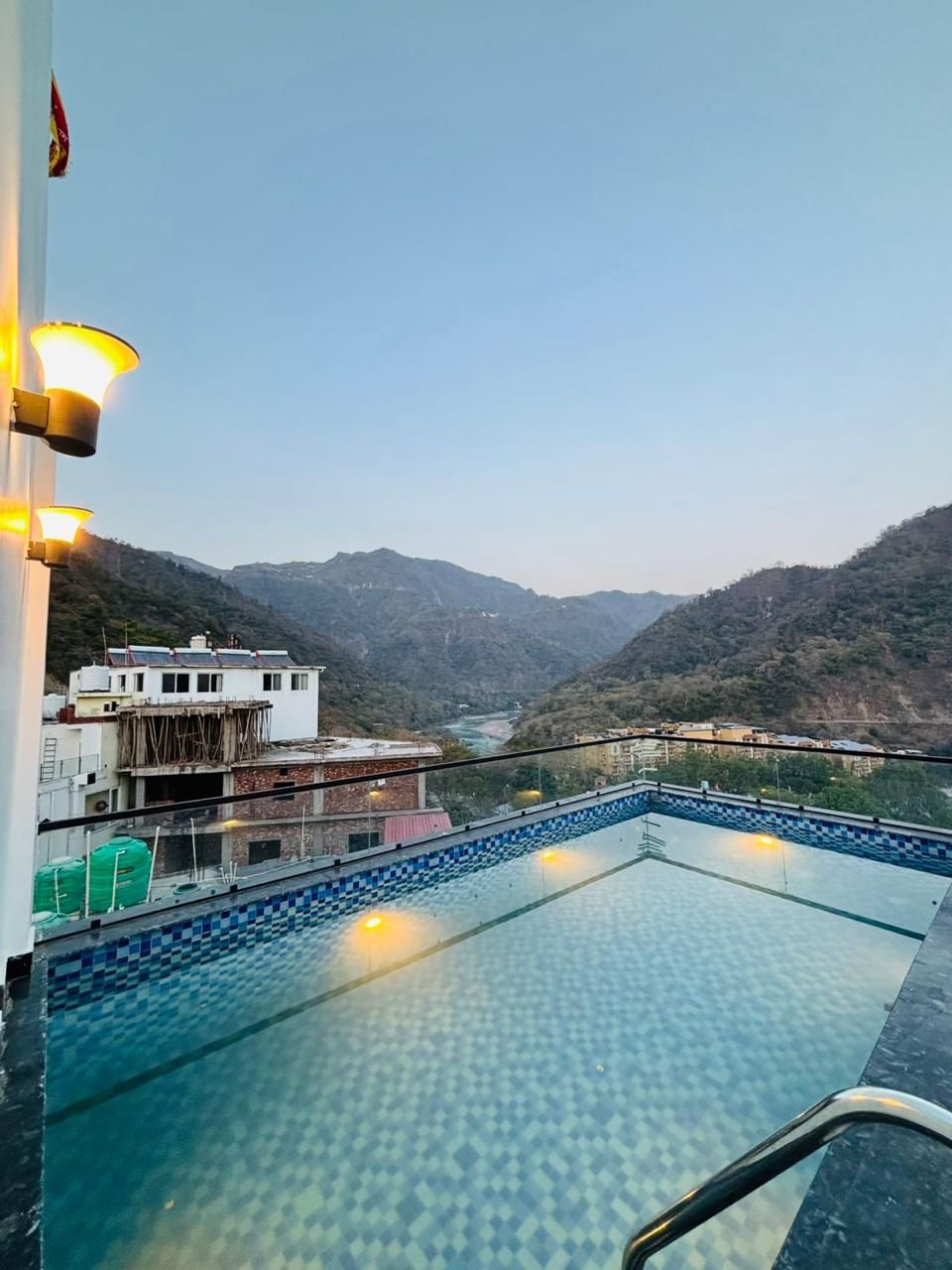 Ein Pool mit einem Kachelmuster, umgeben von einem Geländer, mit Blick auf eine bergige Landschaft im Hintergrund.