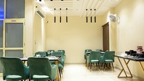 Un salón de conferencias con sillas color turquesa, una mesa negra y una señal de salida de incendios.