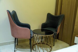 A small room with two chairs and a round table. - Hotel Hrishikesh High Tapovan 2.0 (Rishikesh)