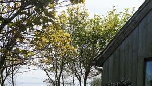 Een rustiek houten gebouw met een tuin, een houten bank en uitzicht op het water.
