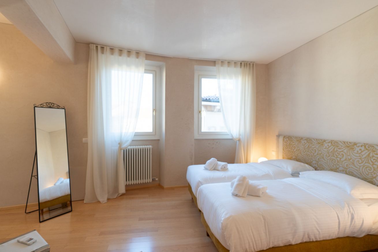 Habitación de hotel con dos camas, un espejo grande y un radiador.