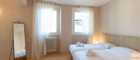 Habitación de hotel con dos camas, un espejo grande y un radiador.