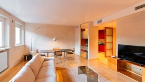 A modern living room with a sofa, dining table, chairs, a TV, and a kitchen area. - Stunning residence with unique view of the Arena (Verona)