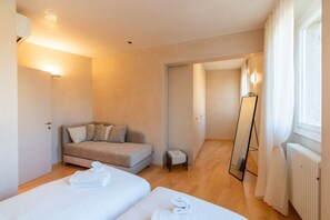 Habitació d'hotel amb dos llits, un sofà, una taula petita, un mirall i un radiador.