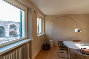 A room with a large window, a radiator, a table with chairs, and a lamp. - Stunning residence with unique view of the Arena (Verona)