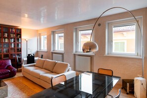A modern living room with a glass dining table, a sofa, a bookshelf, and a radiator. - Stunning residence with unique view of the Arena (Verona)