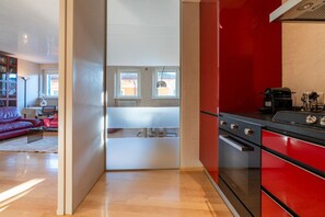 A kitchen with red cabinets, a black stove, and a window with a view of the outside. - Breathtaking residence with a unique view of the arena (Verona)