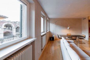 A modern interior with a dining area, a sofa, and a view of an outdoor brick structure. - Stunning residence with unique view of the Arena (Verona)