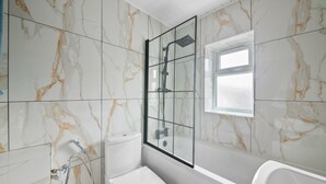 A bathroom with a glass-enclosed shower, a toilet, and a bathtub.