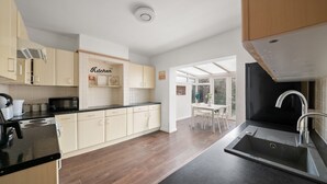 A modern kitchen with wooden cabinets, a black countertop, and a stainless steel sink.