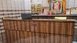 Un comptoir d’accueil avec un sol en marbre, un panneau indiquant les heures d’enregistrement, ainsi que diverses statues et objets religieux exposés.