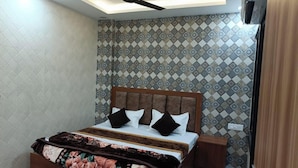 Une chambre à coucher avec un lit, un ventilateur de plafond, une table de chevet et un papier peint à motifs.