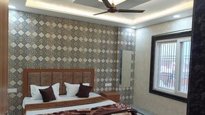 Un dormitorio con pared estampada, ventilador de techo, cama con almohadas y ventana con barrotes.
