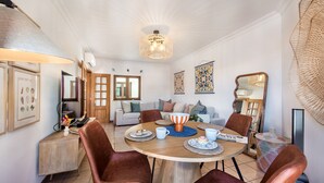 A dining area with a round table, brown chairs, a coffee table, and a hanging light fixture.