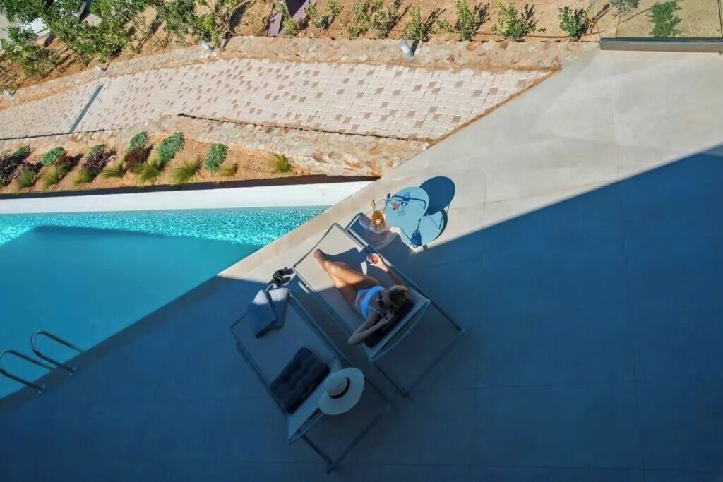 A poolside area with lounge chairs and a person lying on one of them.