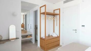 Un dormitorio con un armario de madera, una mesita de noche, un espejo y una puerta.