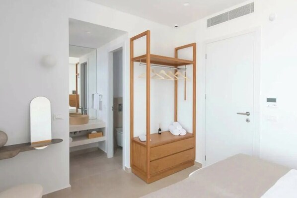 Un dormitorio con un armario de madera, una mesita de noche, un espejo y una puerta.