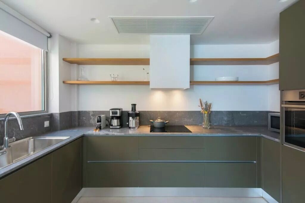 A modern kitchen with a built-in oven, a coffee maker, and a pot on the counter.