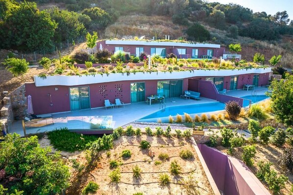 A modern villa with a rooftop garden, a swimming pool, and a hillside view. - Plethora Luxury Suites (Malevizi)