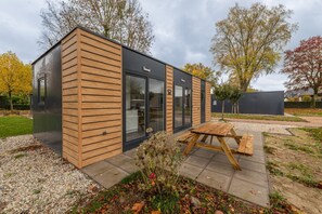 A modern, single-story building with a wooden exterior and large glass windows. - Cube 1 | 4 persoons chalet in Zennewijnen (Zennewijnen)