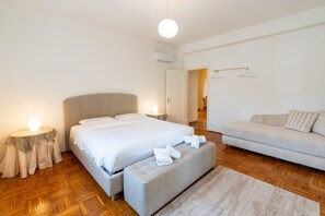Ein Schlafzimmer mit Bett, Nachttischen, einer Couch und einer Hängeleuchte.