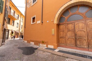 Eine Kopfsteinpflasterstraße mit einem Gebäude, das eine große Holztür und ein Fenster mit Ziegeln aufweist.