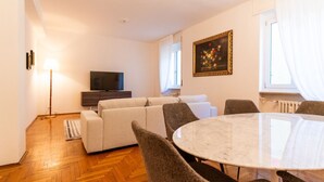 Un salon comprenant un canapé, un téléviseur, une table à manger et des chaises.