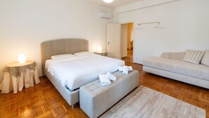 Une chambre à coucher comprenant un lit, des tables de chevet, un canapé et un luminaire suspendu.